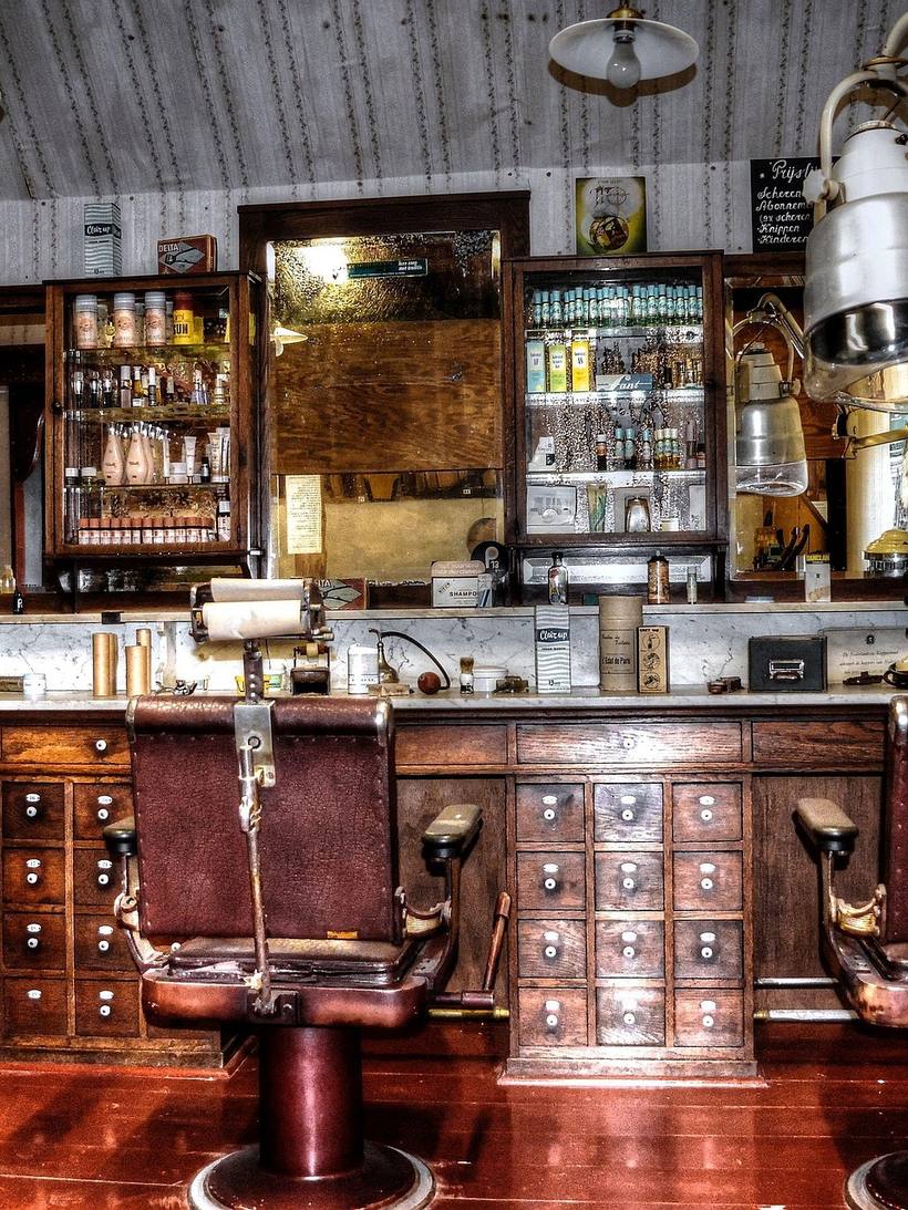 Blick in den Laden: Spiegel, Holztheke, zwei Barbierstühle